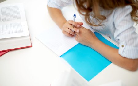 education, people, children and learning concept - girl with book writing to notebook at school